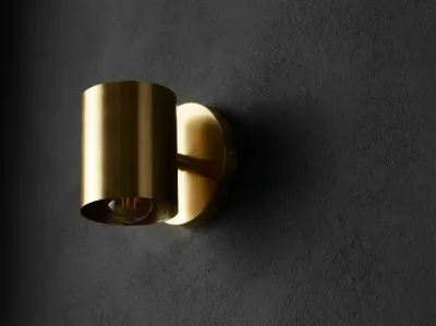 Contraste entre une applique dorée et un mur gris anthracite foncé.