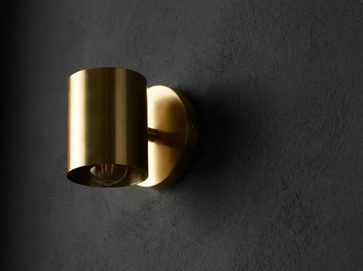 Couleur foncé : guide déco pour un intérieur de caractère Contraste entre une applique dorée et un mur gris anthracite foncé.