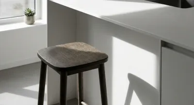 Détail minimaliste d'un tabouret design sous un comptoir de cuisine compacte.